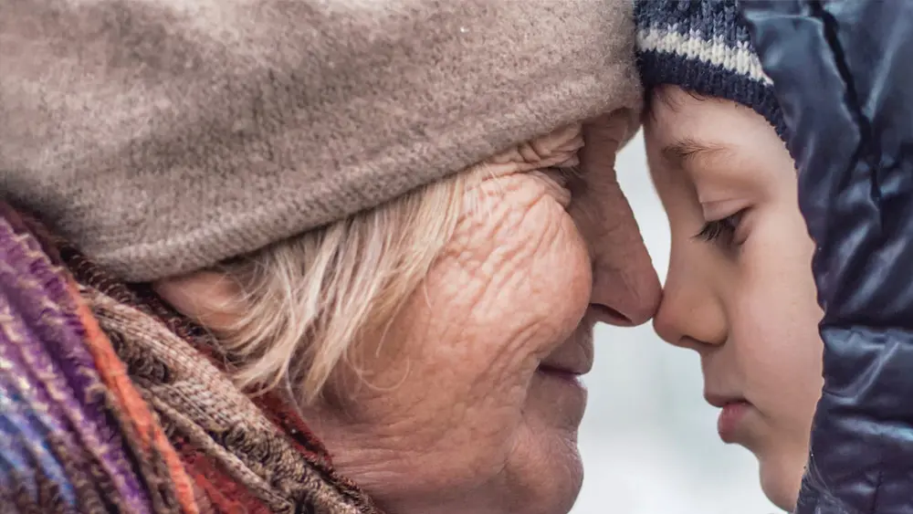 Elderly person touching nose with child