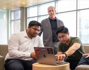 People sitting around a laptop